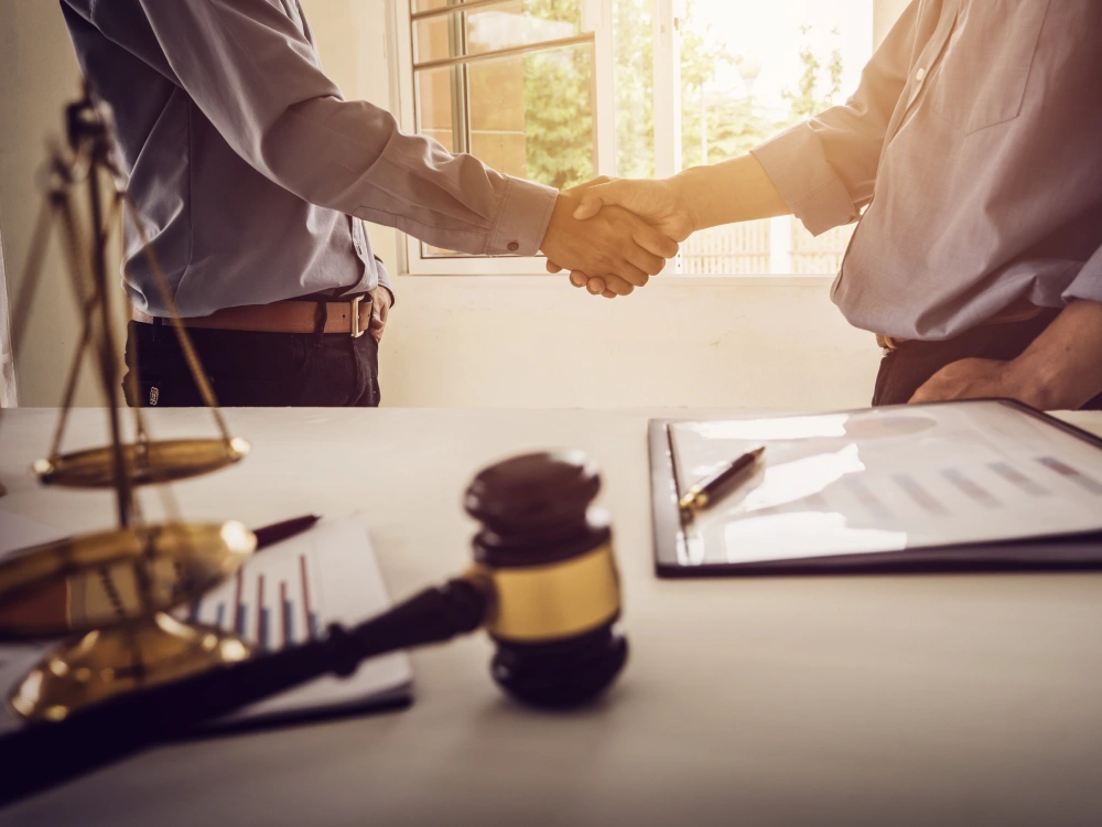 Handshake over legal documents representing claims and dispute support